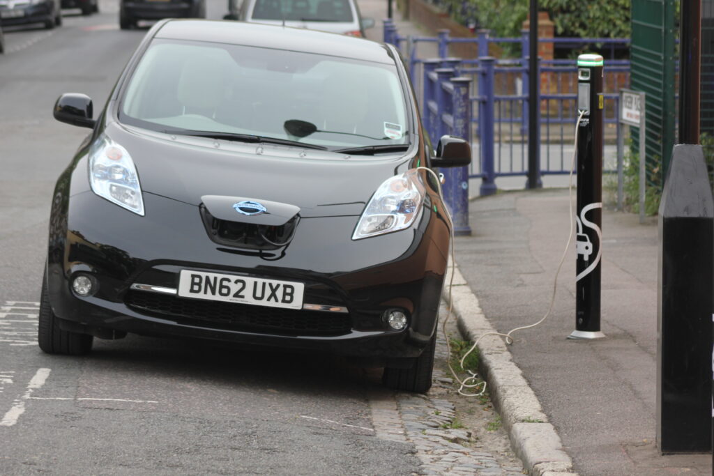 black electric car on the side of a street charging up its battery