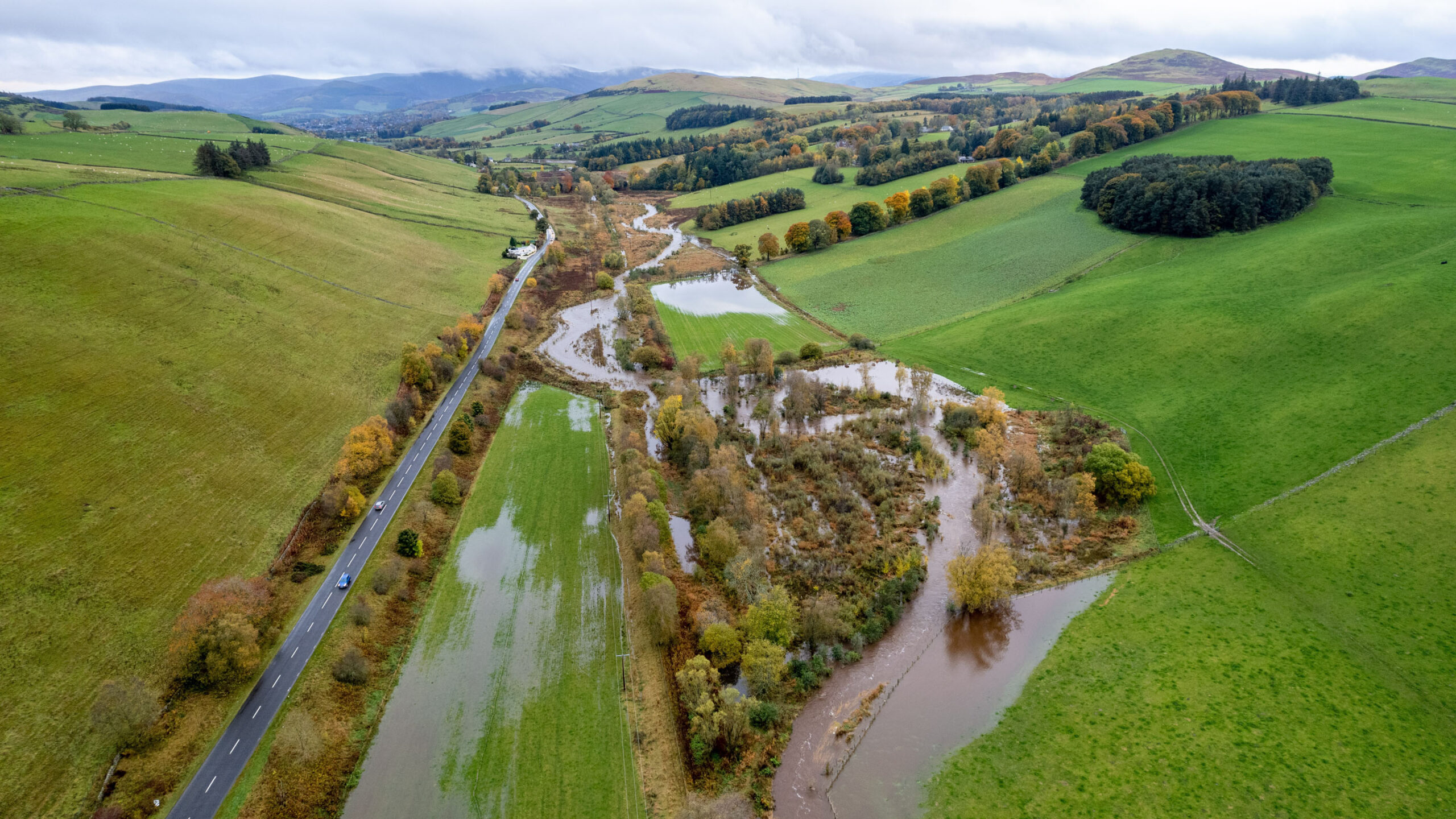 Aerial image of a straight river being redirected around some trees at the Eddleston Water Project. The Eddleston water Project has involved a number of natural flood management measures, such as re-meandering straightened river channels. Image taken by Colin McLean.