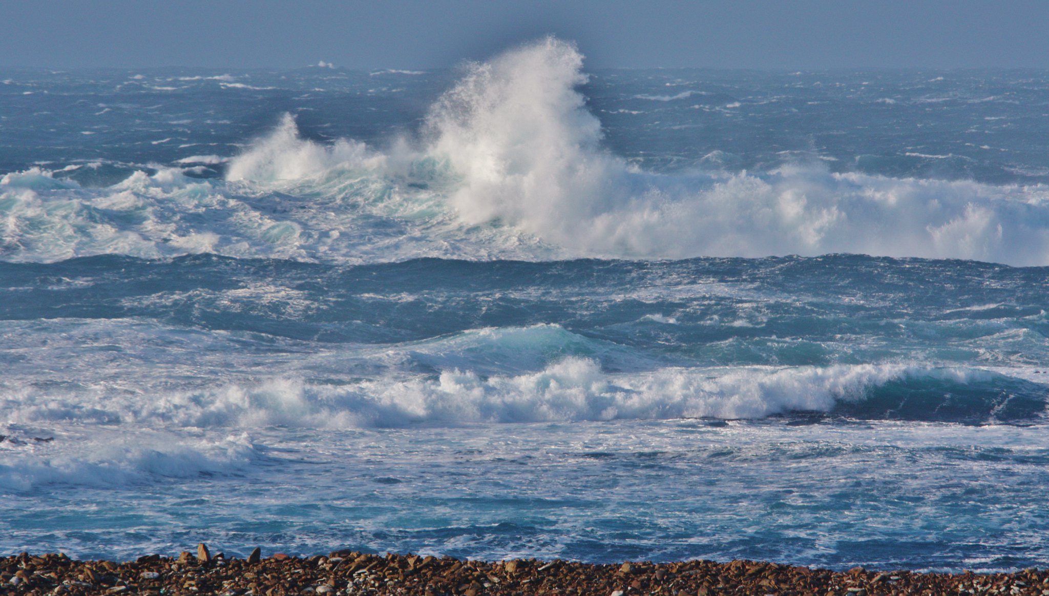 Stormy sea and waves crashing against a stony beach.