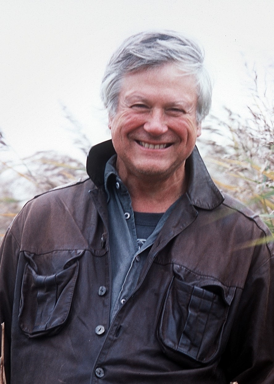 Portrait of Richard Mabey stood in front of some trees.