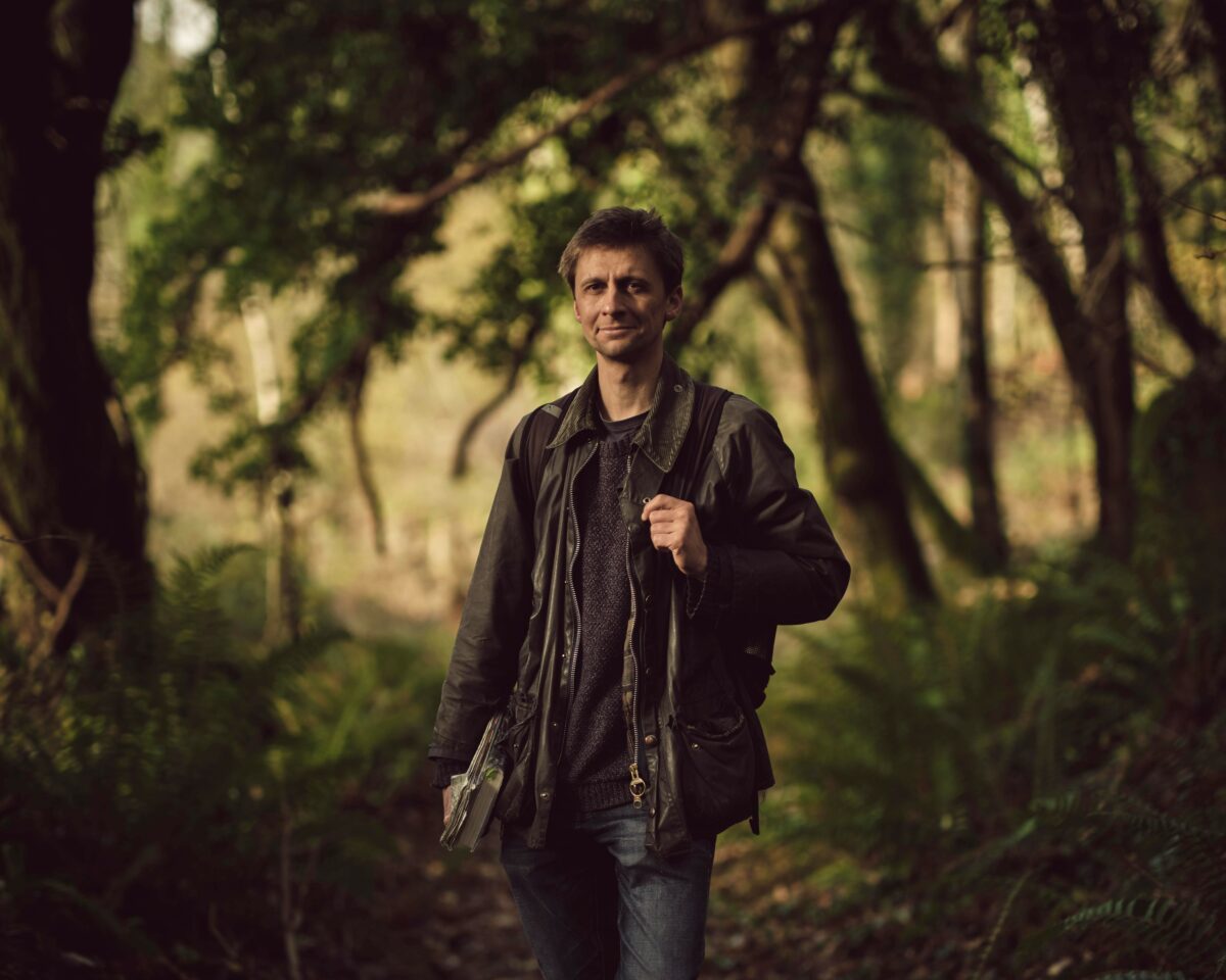 Author portrait of Guy Shrubsole in a forest.