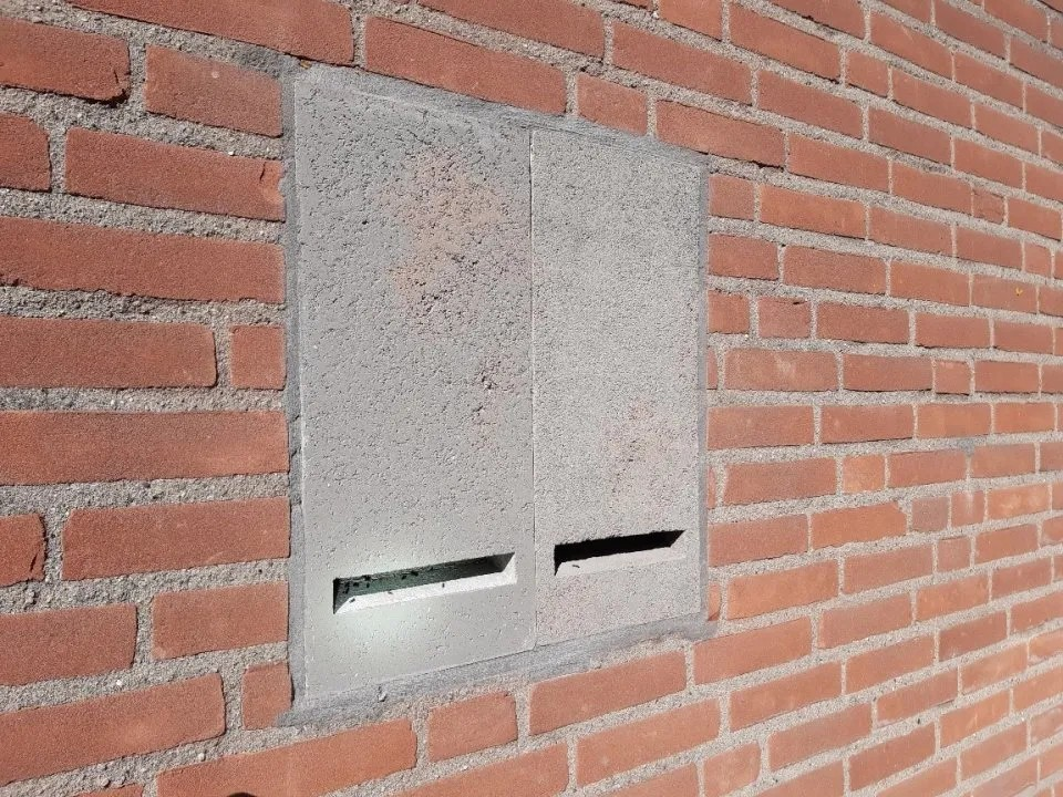 A large grey concrete box built into the wall with a thin slit at the bottom edge