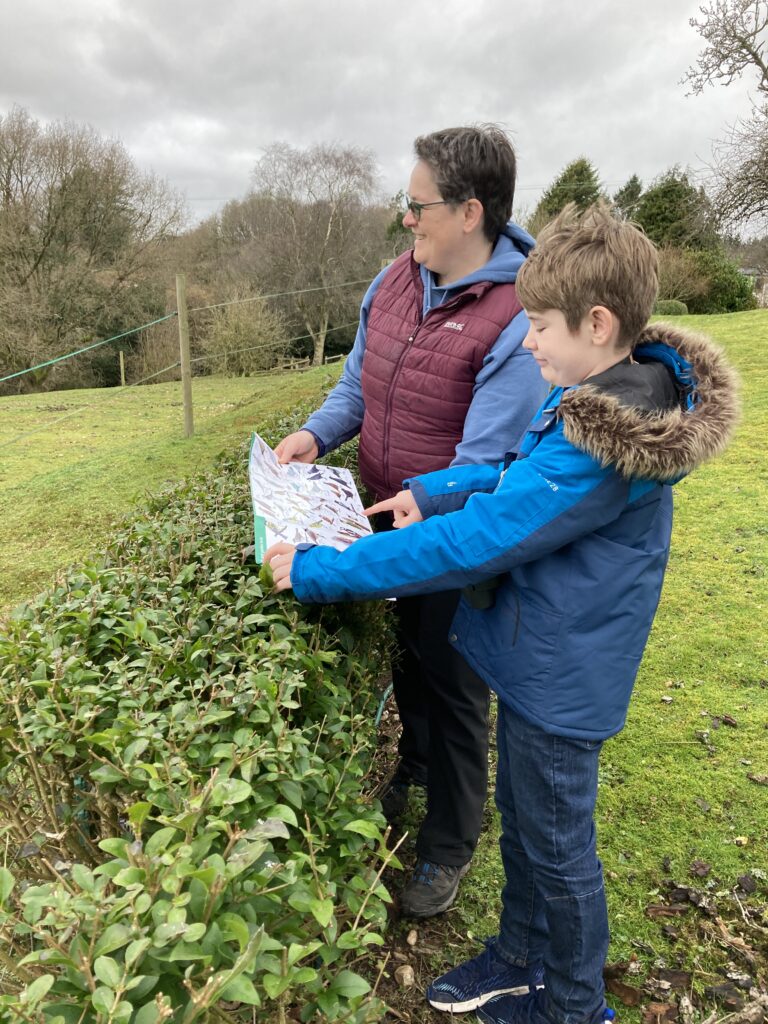 Two wildlife watchers using a Field Studies Council WildID Bird guide in a local field