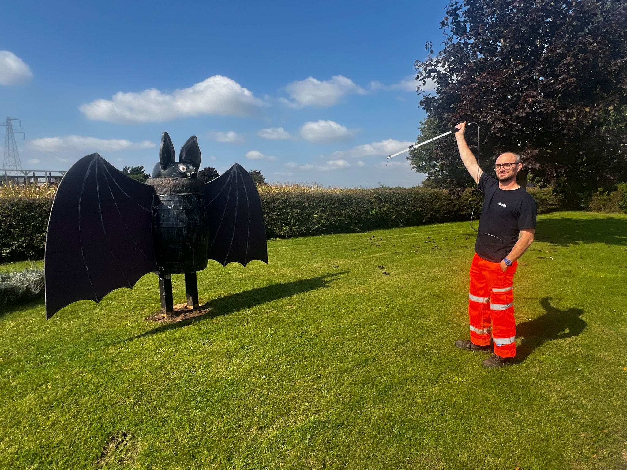 James Shipman holding a bat detector pointing at a giant plastic pretend bat.